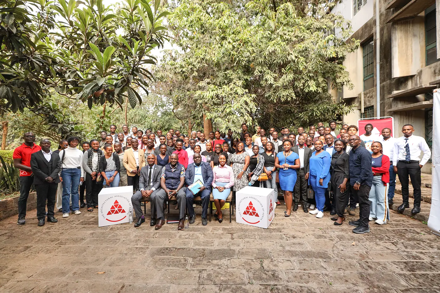 Participants and AAK members in a group photo in a garden courtyard